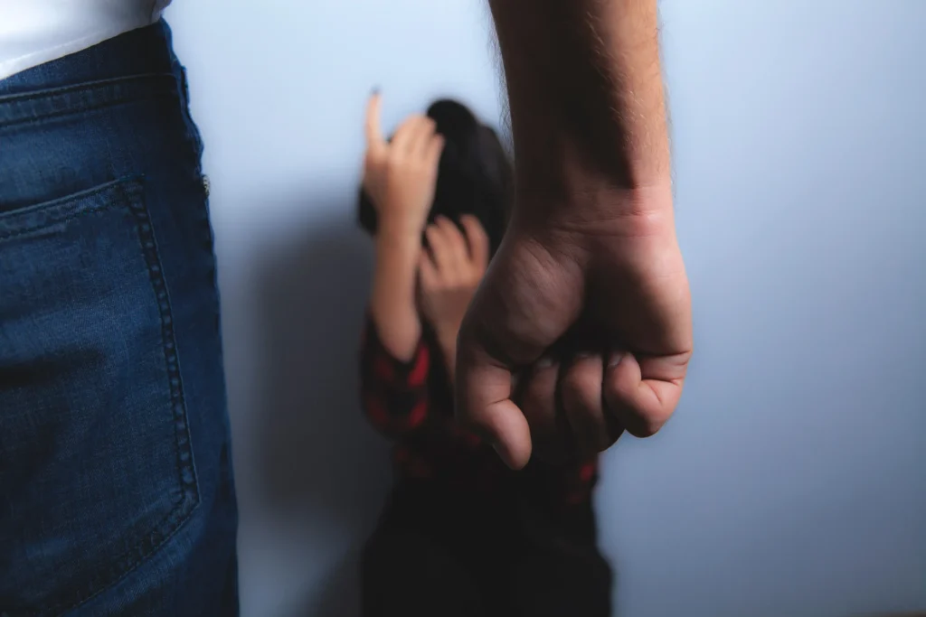 A man with a clenched fist standing in front of a scared woman.