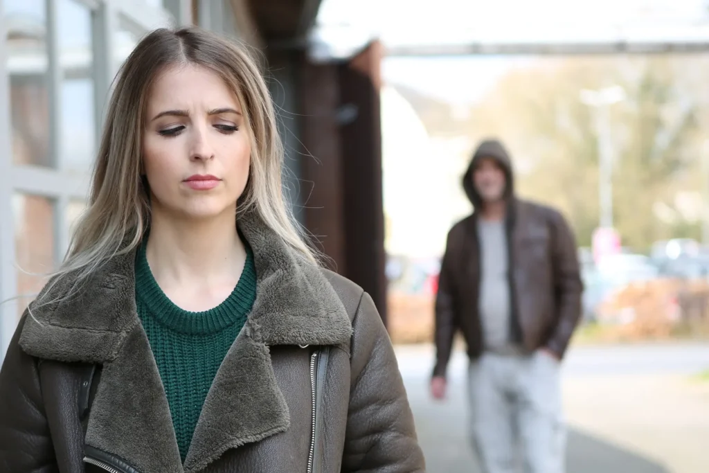 A man following a woman and she is looking back and worried,
